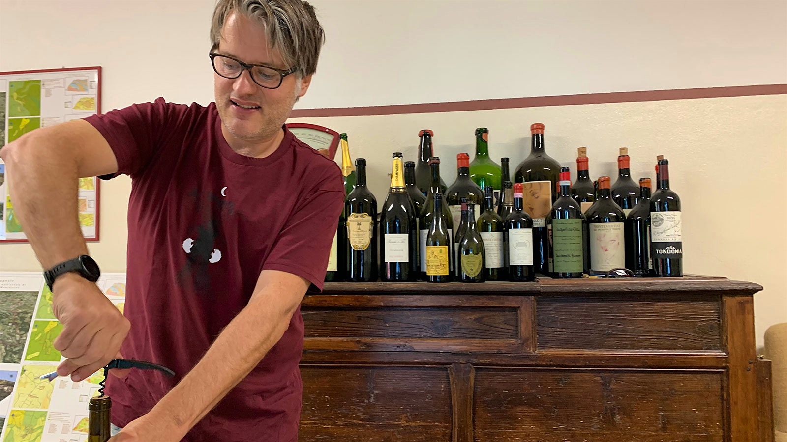 Brunello producer Riccardo Campinoti opening a bottle in front of a collection of top wines from other regions of the world